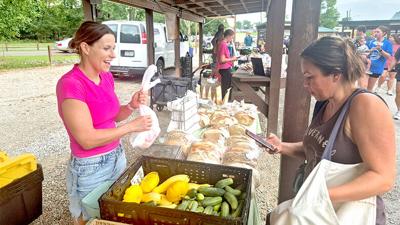 Apryl Ott of Julie’s Produce, left, completes a sale Aug. 19 with Aleisha Althage of Arnold during the Farm Fresh at Sunset market. It was the first evening weekday market held at the Arnold Farmers Market.