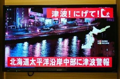 A tsunami advisory flashes over the live footage on a TV screen in Sapporo, in Japan's north