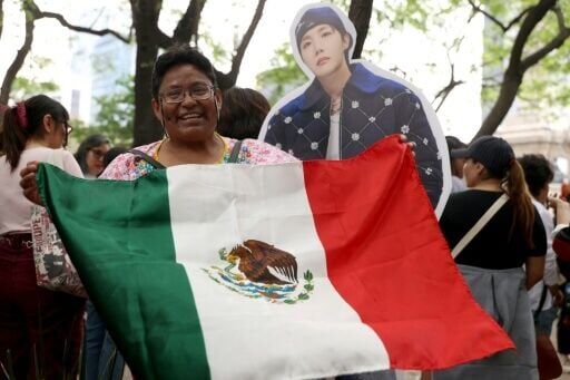 Una mujer muestra una bandera de México junto a una figura de cartón de J-Hope, cantante surcoreano de K-pop del grupo BTS, durante una reunión de fans en la Ciudad de México el 3 de mayo de 2026.