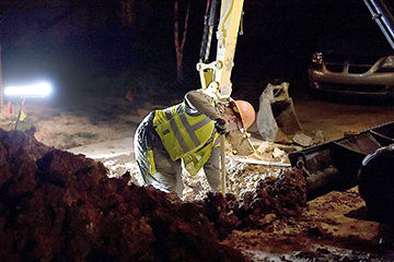 A utility worker from Spire Inc. works to locate a broken gas line.