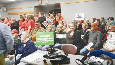 People hold signs either supporting or opposing a potential data center in Festus.
