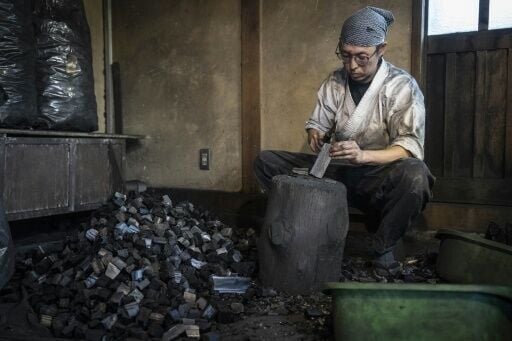 Apprentice Toru Watanabe breaks charcoal into smaller pieces for the forge at a workshop in Misato, Saitama prefecture