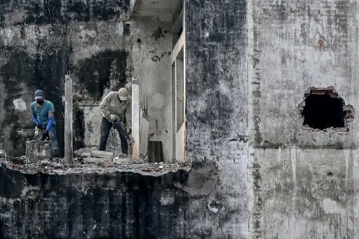 Workers dismantle part of a building at a demolition site in Hanoi on December 10, 2025.