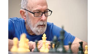 Tom McGrath analyzes chess pieces on May 26 at Crystal City Public Library. McGrath founded the club in 2023, hoping to share his own love of chess with the community.