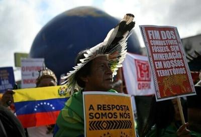 Indigenous people hold signs reading "The answer is us" and "End of fossil fuels, no mining in our territories" during a march on the sidelines of the COP30 UN Climate Change Conference in Belem, Brazil