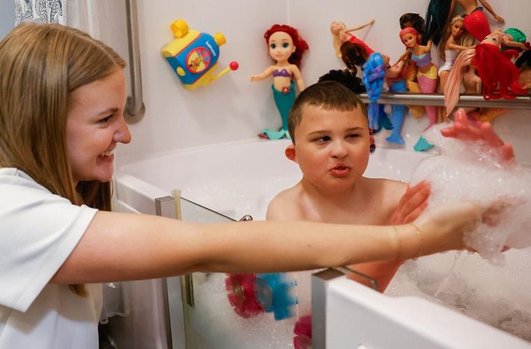 Emma Stockstill, left, one of Carter’s caretakers, holds up bubbles to Carter