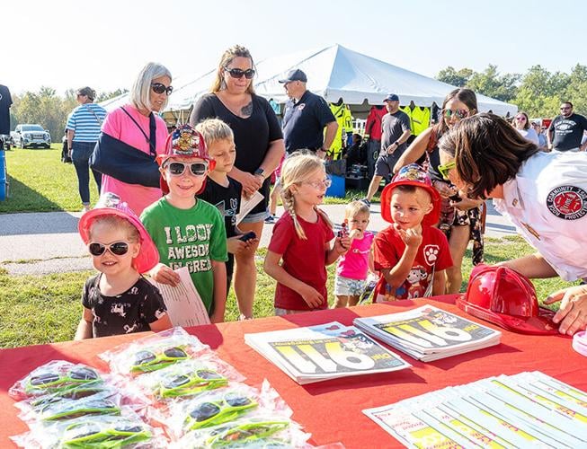 At left, siblings Everly Gutknecht, 3, and Knox Gutknecht, 6, both from Crystal City, visit Rock Community Fire Protection District’s table for hats and sunglasses