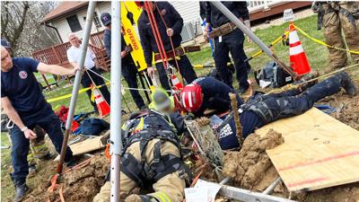 Rock firefighters work to rescue a man trapped in a hole