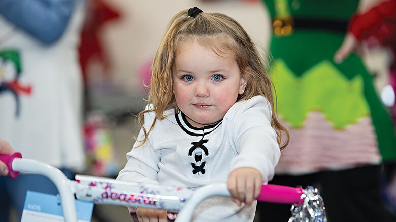 Lacie Dalton, 3, shows off the new bike she won at the 2024 Arnold Kiwanis Giving and Light Fair.