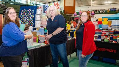 Carrie Wolk at her Tupperware booth visits with customers, Sandy Meuer and Tiffany Johnson of De Soto.