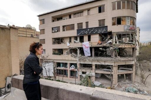 A woman surveys damage to a Tehran building that housed the offices of Qatari news network Al Araby TV following a missile strike
