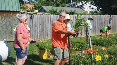 Carrol Wrather’s son, Dale, digs up lilies for Margie Weber of Dittmer, left, at last year’s daylily sale.