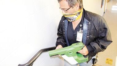 Festus R-6 School district custodian Aaron Gurnow uses an electrostatic sprayer to disinfect handrails at Festus High School.