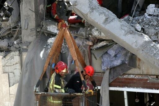 Firefighters try to recover the body of a victim in a damaged building in southern Tehran