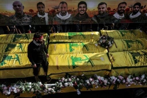 Coffins sit on a trailer beneath portraits of Hezbollah fighters killed in Lebanon by Israel before a 10-day ceasefire was agreed