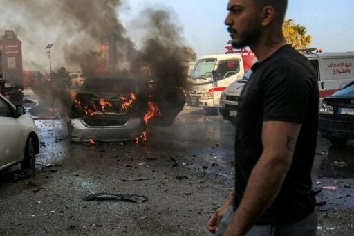 A man walks near a burning vehicle that was targeted by Israeli bombardment in Lebanon's southern coastal city of Sidon on March 18, 2026.