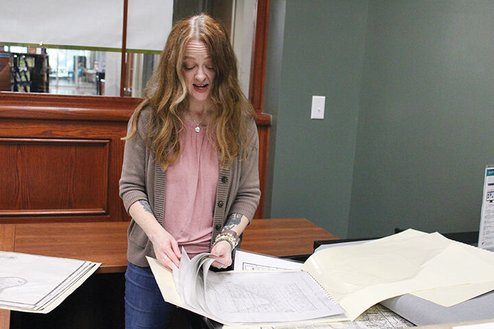 Genealogy Library Associate Ginger Brickey flips through old county maps available at the Jefferson County Genealogy Department, with some dating back to before the Louisiana Purchase in 1803.