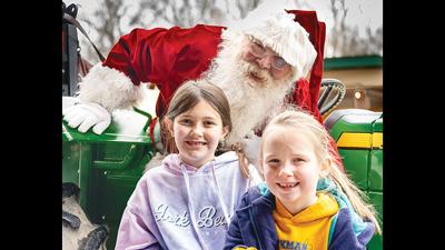 Santa Claus leans in for a photo with sisters Kate Sartors, 9, and Sarah Sartors, 6, both from Imperial, at the Arnold Christmas Market.