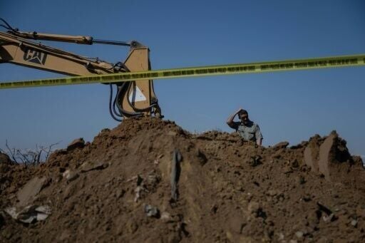 A forensic expert observes a bulldozer excavating a suspected mass grave near Rahovec