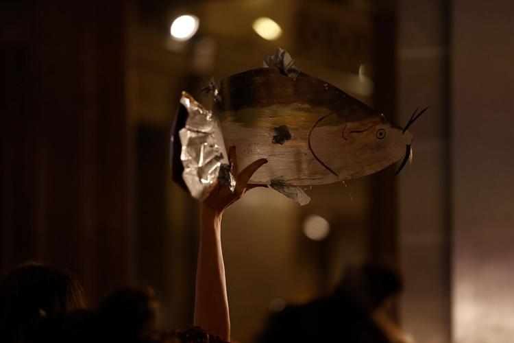A protester holds up a handcrafted fish prop