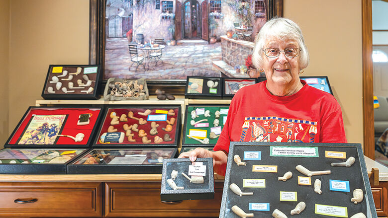 Kathie Roussin of De Soto holds display cases of colonial clay pipes.