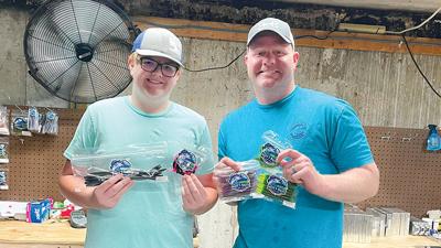 Nate and his dad, Aaron Cizek, hold up some of the baits they make together in their basement.
