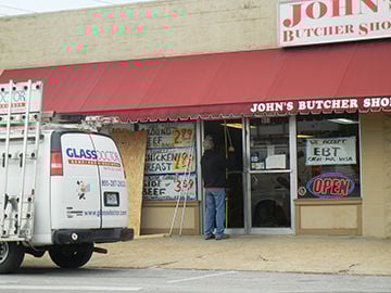 A repairman works to replace glass broken during a burglary at John's Butcher Shoppee in Festus.