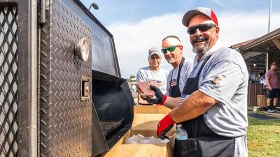 Scream Team volunteers Tim Hahn and Ronnie Mueller, both From Cedar Hill, fire up the grill at the BackStoppers BBQ.