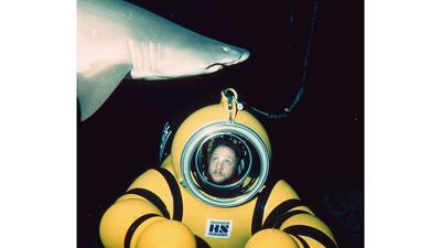 Robert Mester dives near a shark while speaking to students via radio.