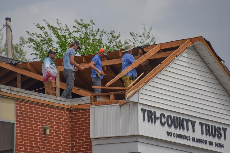 Roofers begin to rebuild the roof of the Tri-County Trust Company