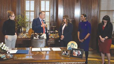 Gov. Mike Kehoe speaks to Rep. Cecelie Williams before signing her marriage-dissolution bill into law.