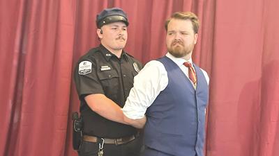 A police officer, played by Jacob Fisher, arrests General Bullmoose, played by Kameron McClinton.