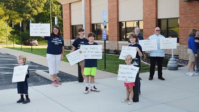 Before the County Council’s vote, people hold signs in support of opening a transitional housing center near Hillsboro.