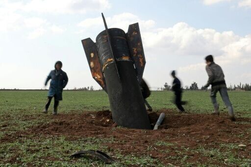 Children play around an unexploded missile that landed in an open field on the outskirts of Qamishli, eastern Syria