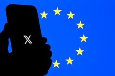 The logo of social network X is displayed on a smartphone in front a Euopean Union flag in Brussels
