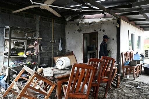 A security guard inspects an evacuated house that was hit by Cambodian artillery in Thailand's Surin province