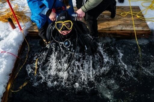 A participant in the Polar Scientific Diving program is lifted out of the water by colleagues