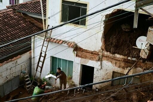 Volunteers remove a birdcage as they search for victims amid the rubble and mud of a house after a landslide triggered by heavy rains