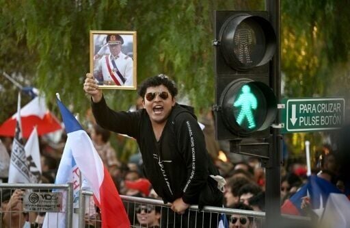 A man shows a portrait of the late Chilean dictator Augusto Pinochet (1973–1990) following the first results of the presidential runoff election in Santiago on December 14, 2025.