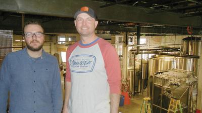 Six Main general manager Tyler Bryant, left, and Main & Mill Brewing Co. co-owner Denny Foster in the rear area of the building that houses Main & Mill’s brewing vats.  The front of the building is slated to become bar, restaurant and tasting room spaces.