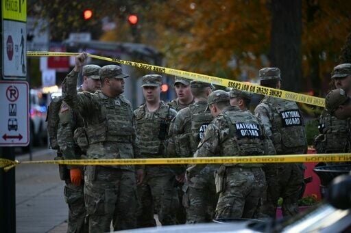 National Guard soldiers stand behind crime scene tape at a corner in downtown Washington where two National Guard soldiers were shot just blocks from the White House