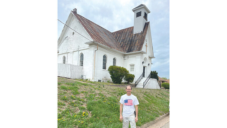 Paul Wheelhouse stands in front of a historic church in De Soto that was built in 1866 and first used as a schoolhouse.