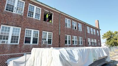 Workers from Wellington Environmental remove windows from the former Sacred Heart Catholic School building in Festus.