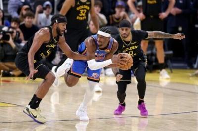 Oklahoma City Thunder star Shai Gilgeous-Alexander drives against Moses Moody and Gary Payton II of the Golden State Warriors