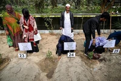 Family members mourn at the graves of relatives after their identification by an investigative commission at the Rayerbazar Graveyard in Dhaka