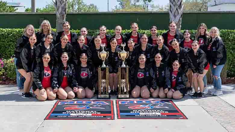varsity and jv warriorettes outside with trophies