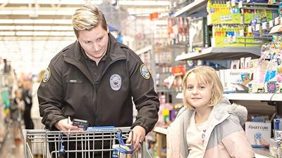 Officer Herold of the Arnold Police Department shops with Kinzlee Struebig, 8, of Fenton at Walmart during the 2022 Shop with a Hero event.