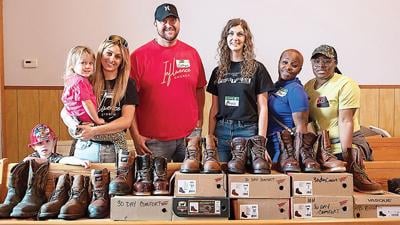 From left, Influence Church members Weston Waddington, 5, Rowynn Abeyta, Sarah Abeyta, Nathan Bauwens, Kayce Waddington, Shawn Lewis and LaTaurus Jones with boots they collected for the Project Homeless Connect event held in April.