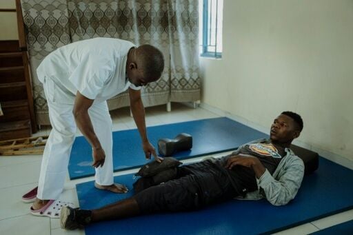 A patient, who lost a limb and is being cared for by the Red Cross, sits on rehabilitation mats