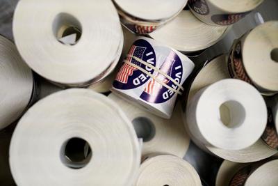 Rolls of “I Voted” stickers sit in a banker box in the County Clerk’s offices
